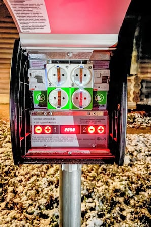A utility meter with two sockets, a label with text, and a red warning sign.