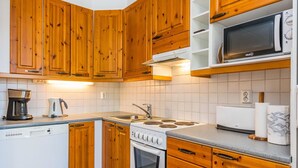 Una cocina compacta con armarios de madera, estufa, microondas y lavavajillas.