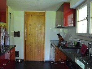 A kitchen with a wooden door, stainless steel appliances, and a window.
