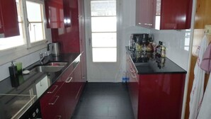 A compact kitchen with red cabinets, a stainless steel sink, and a window providing natural light.
