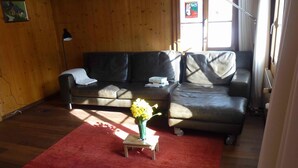 A living room with a red carpet, two sofas, a small table with a vase of flowers, and a lamp.