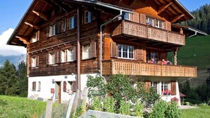 Een houten chalet met balkon, gelegen in een bergachtig gebied.