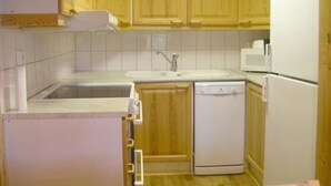 A compact kitchen with wooden cabinets, a white sink, a microwave, and a dishwasher.