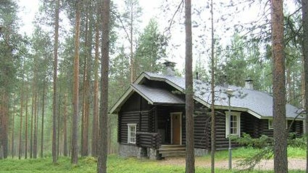 A log cabin surrounded by tall trees in a forest.