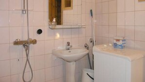 A bathroom with white tiles, a sink, a mirror, and a shower.