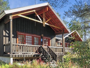 Eine Holzhütte mit einer Veranda und einer Treppe, die zu einer Tür führt.