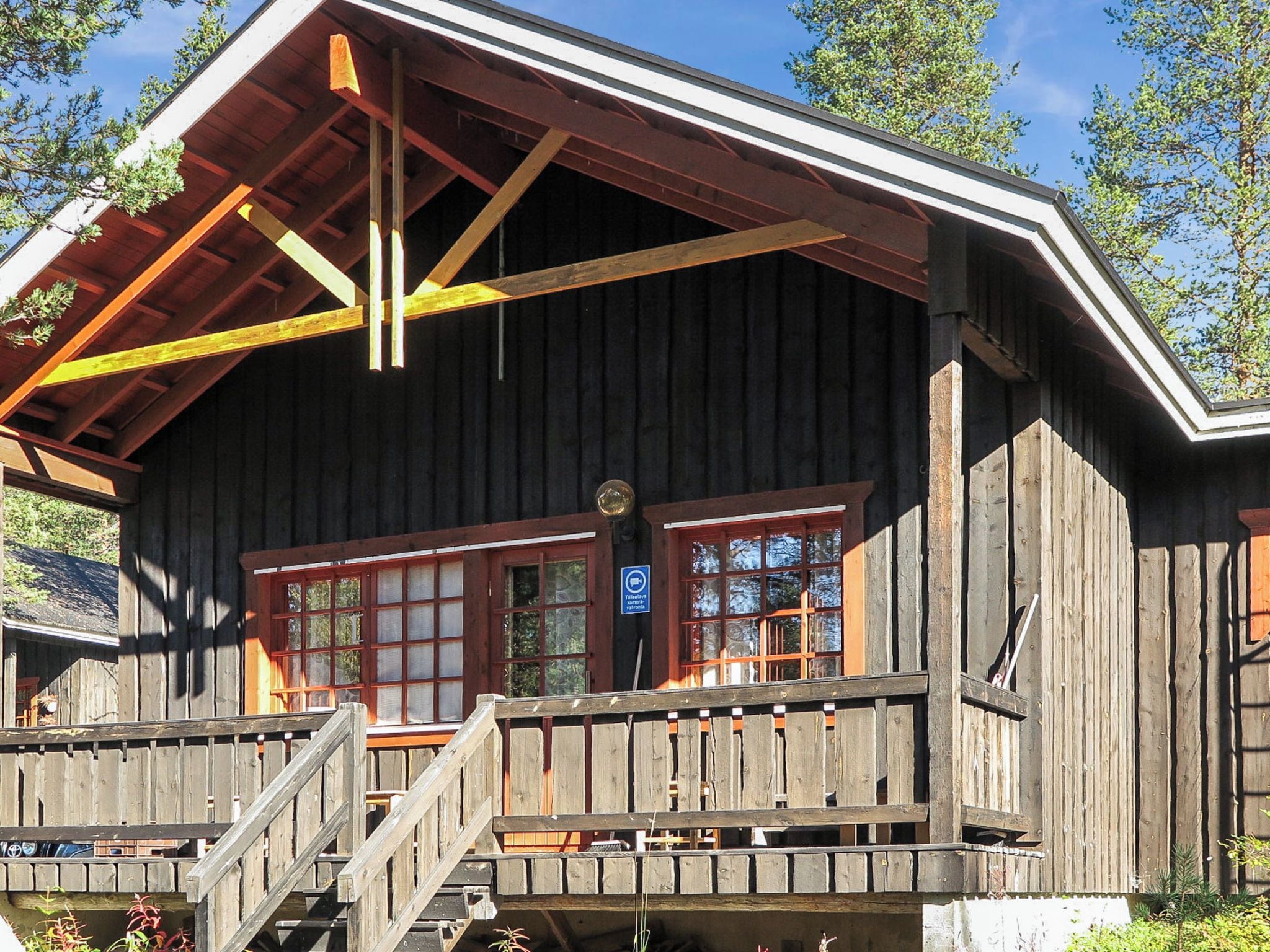 A wooden cabin with a balcony, a staircase, and a sign indicating a sauna.