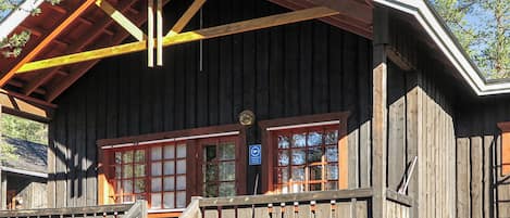 A wooden cabin with a balcony, a staircase, and a sign indicating a sauna.