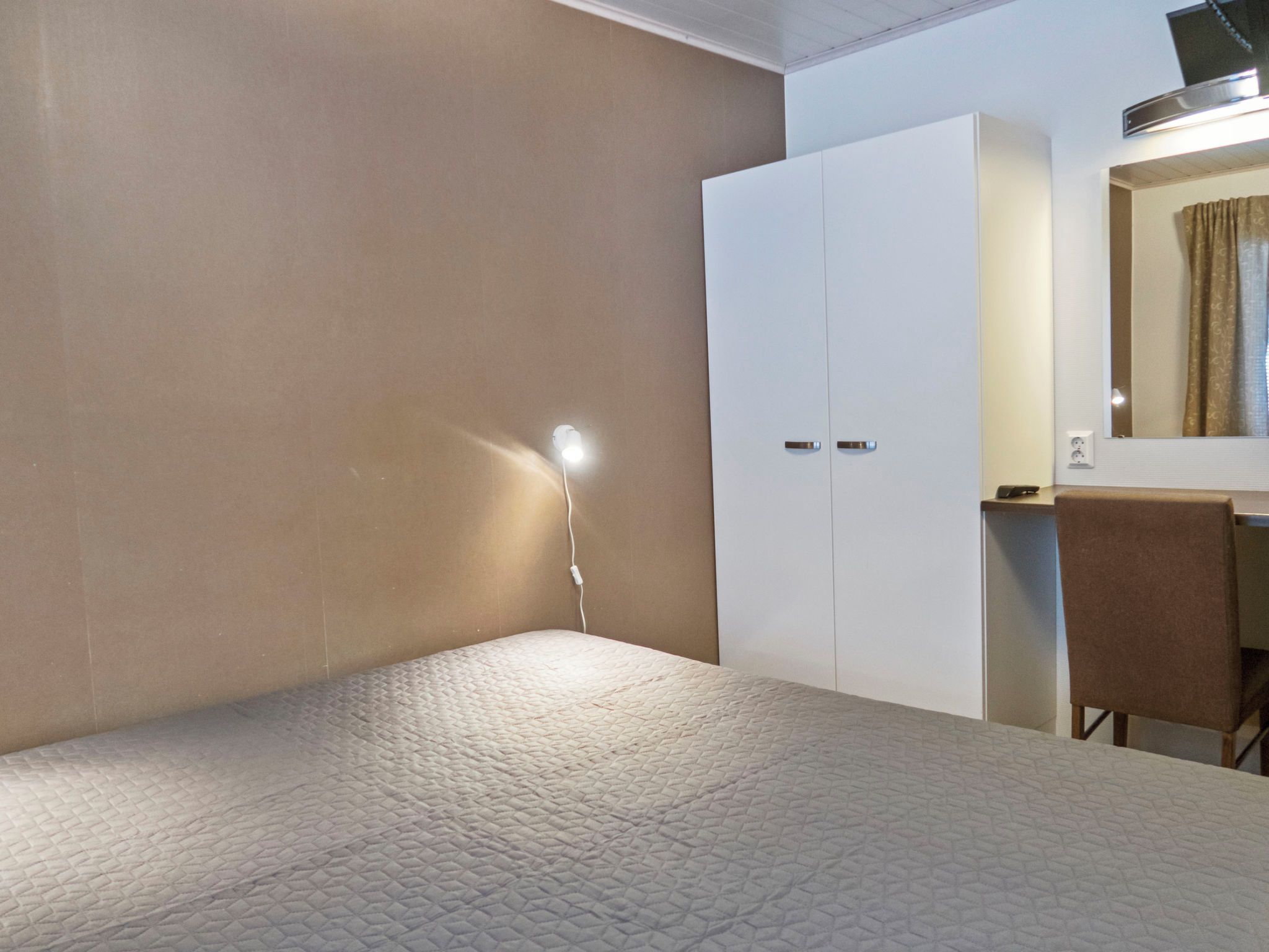 Una camera da letto con un letto, un armadio, una scrivania con una sedia e uno specchio.