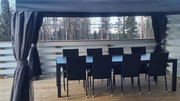 Een overdekt terras met een tafel en stoelen.