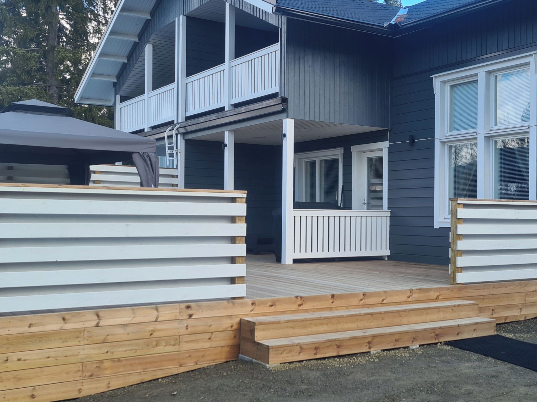 Une maison à deux étages avec un porche couvert et une terrasse en bois.