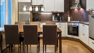 A modern kitchen with a dining table and chairs, built-in appliances, and a large window.