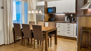 Et moderne køkken med spiseplads, der indeholder et træbord og stole, en indbygget mikroovn og kaffemaskine.