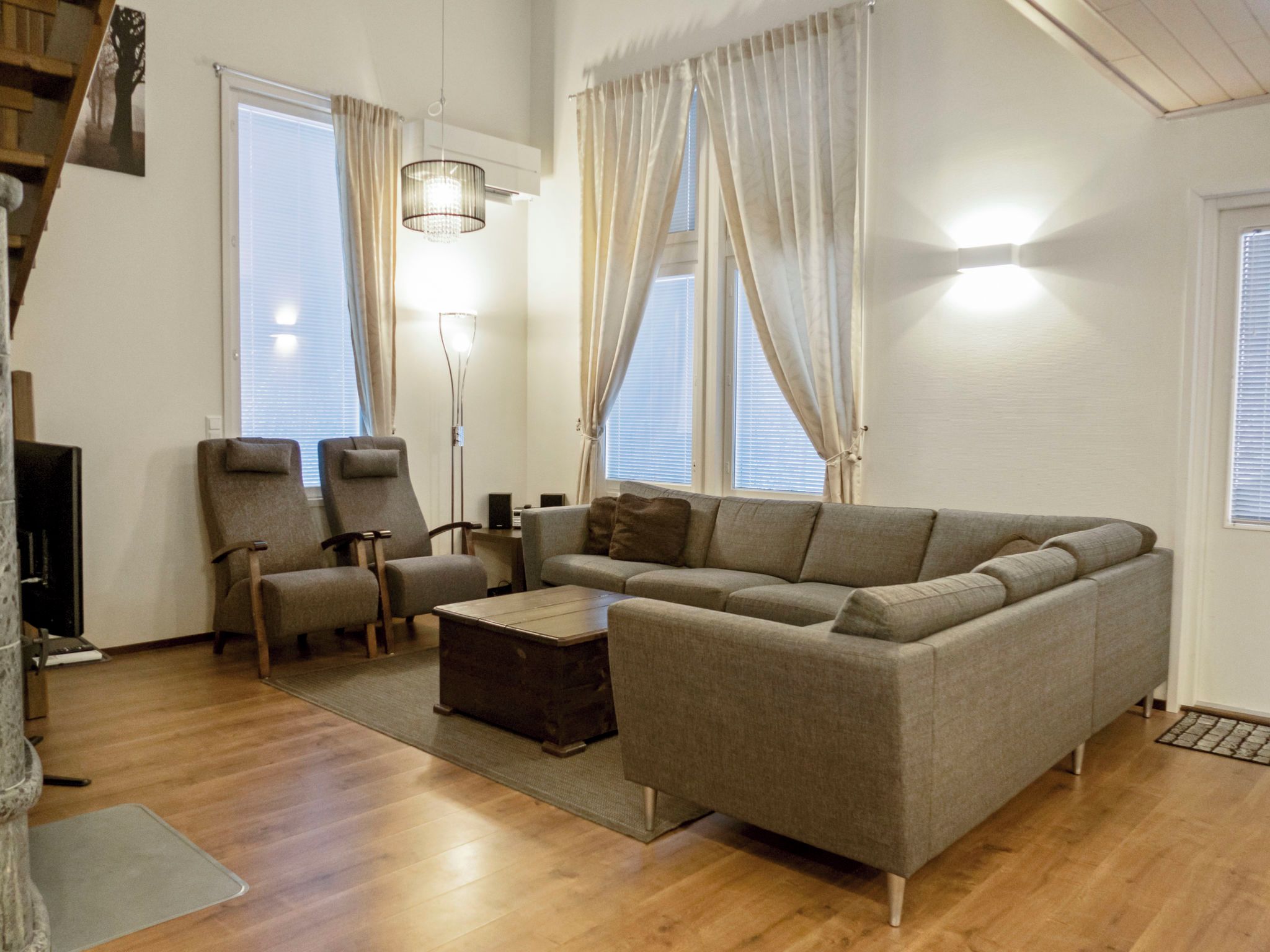 Una sala de estar con sofá, sillones, una mesa de centro y una lámpara de pie.