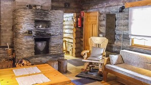 L’intérieur d’un chalet rustique en rondins de bois, avec une cheminée en pierre, des meubles en bois et un coin salon confortable.