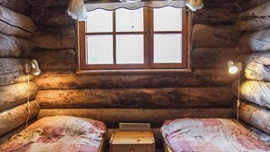 Une chambre de style rustique avec deux lits, une petite table et une fenêtre avec des rideaux.