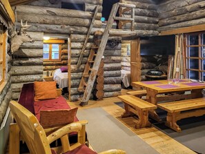 A log cabin interior with a wooden bench, a table, and a ladder.