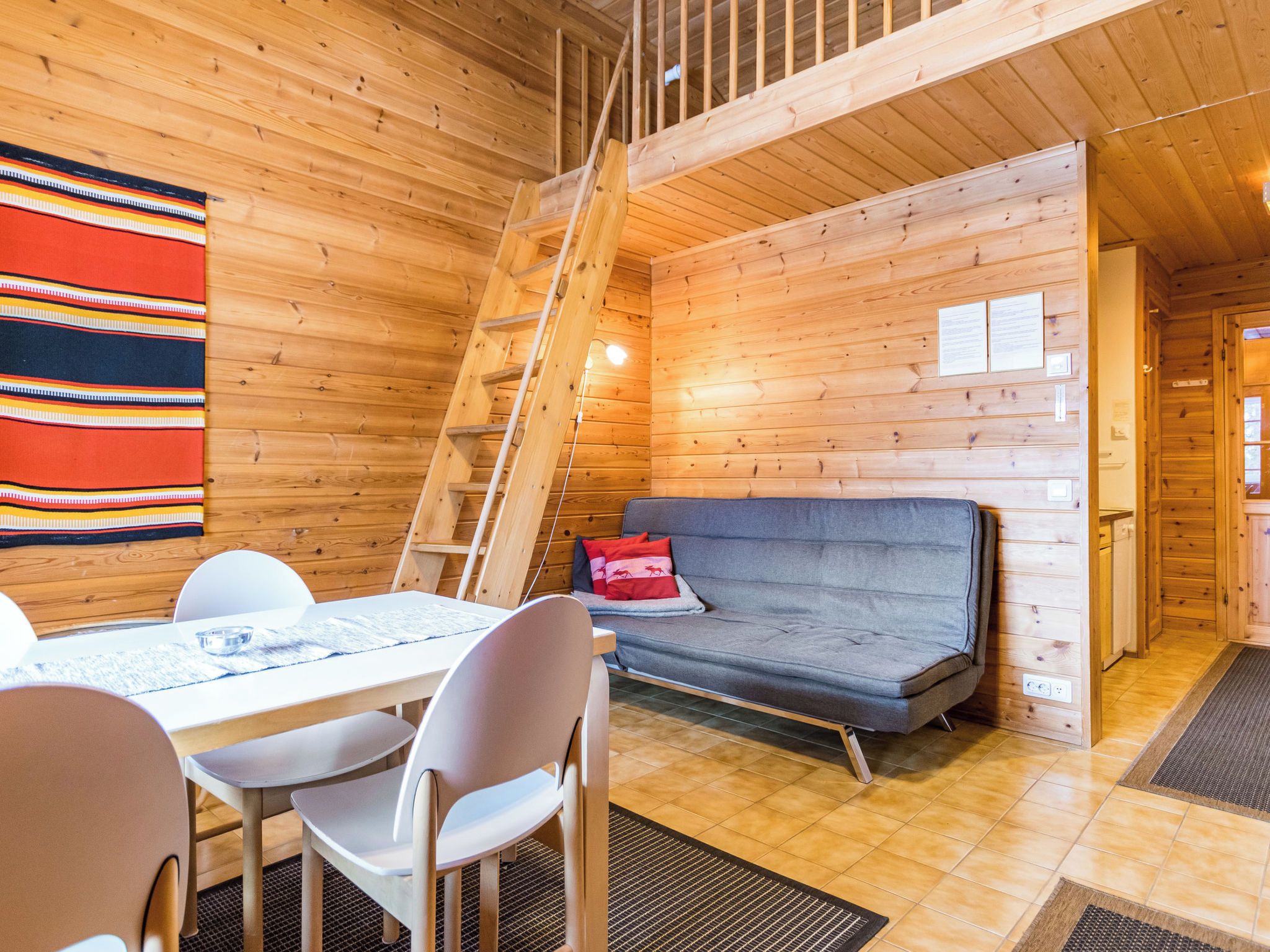 En mysig stuga med en matplats, en soffa och en trätrappa.