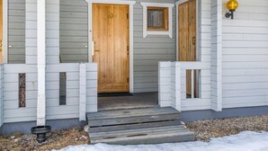 A house with a wooden front door, a small porch with steps, and a mailbox.