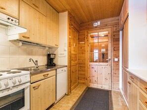 Een kleine keuken met houten kastjes, een fornuis, een koffiezetapparaat en een spoelbak.