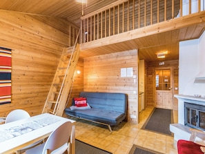 A wooden cabin interior with a sofa, a dining table, and a kitchen area. - Mestarikämpät b10 by Interhome (Kuusamo)