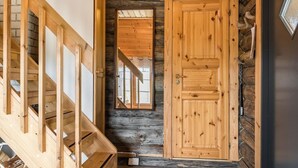 Un escalier en bois mène à une pièce dotée d’une grande porte en bois et d’une petite fenêtre.