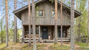 Une cabane en rondins avec un porche à l’avant, deux fenêtres et une porte.