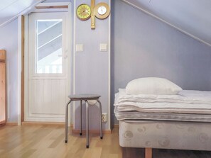 A bedroom with a bed, a small stool, a door, and two wall clocks. - Kerkkälä by Interhome (Sodankylä)