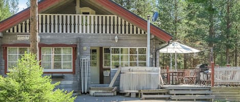 A wooden cabin with a red roof, a porch with a bench, and a sign reading 'KERKKALA'.
