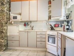 A kitchen with white cabinets, a Bosch oven, a microwave, and a coffee maker. - Kerkkälä by Interhome (Sodankylä)