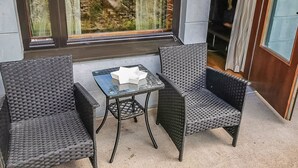 En hyggelig udendørs siddeplads med fletmøbler og et glasbord, med udsigt over et stykke klippelandskab.