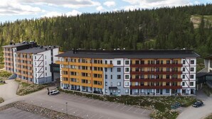 Et hotel med flere etager, moderne arkitektur, og en blanding af altaner samt store vinduer.