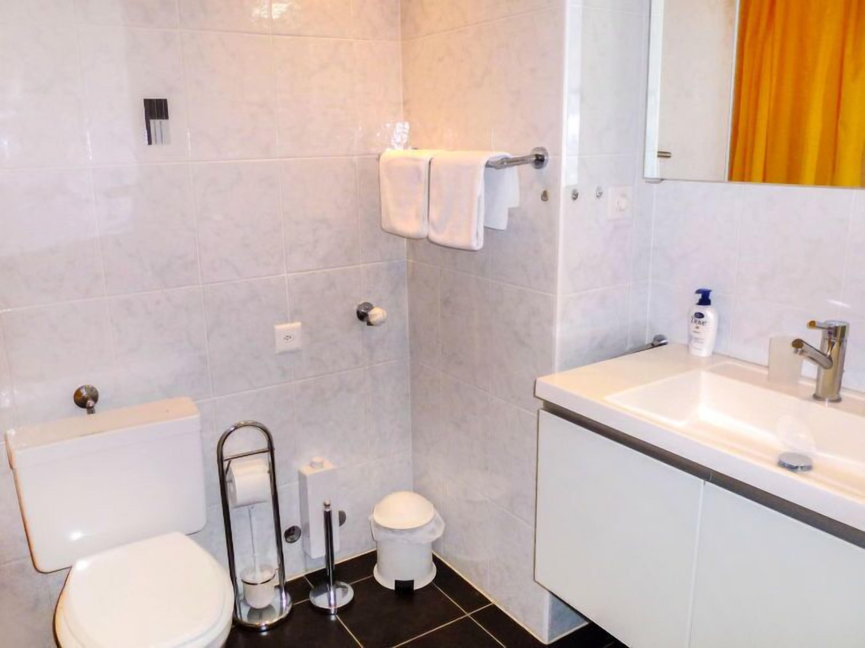 A bathroom with a toilet, bidet, sink, and mirror.