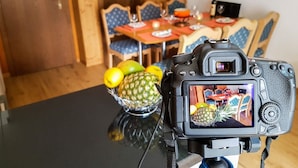 A dining area with a table, chairs, and a camera capturing the scene. - Monte Rosa by Interhome (Saas-Grund)