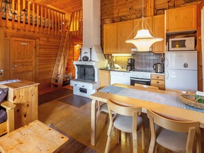 Interior de una cabaña de madera con comedor, cocina y sauna.