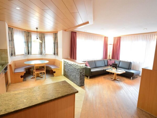 A modern living room with a dining area, a sofa, and a stone accent wall. - Helvetia Apartments by Interhome (Saas-Fee)