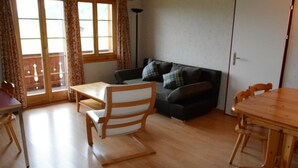 Ein gemütliches Wohnzimmer mit einer Couch, einem Holzesstisch und einem Sessel.