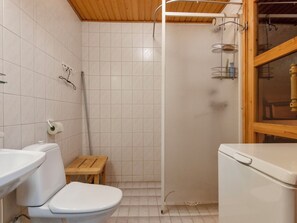 Une petite salle de bain compacte, équipée de toilettes, d’un lavabo et d’une cabine de douche.