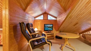 A cozy attic room with wooden walls, a comfortable leather chair, a small table, and a television. - Korpipalo (ent. yllästunnelma 2 b 7) by Interhome (Ylläsjärvi)