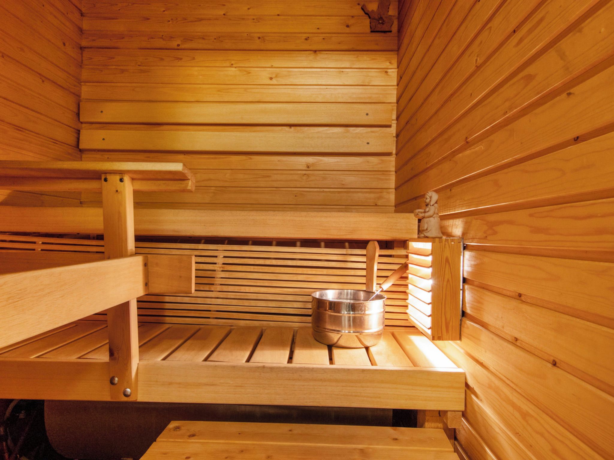 Una sauna con panche di legno e un recipiente metallico, probabilmente per l'acqua o il vapore.