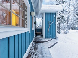 A snow-covered wooden walkway leading to a blue building with a window and a door. - Korpipalo (ent. yllästunnelma 2 b 7) by Interhome (Ylläsjärvi)