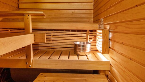 A sauna with wooden benches and a metal container, likely for water or steam. - Korpipalo (ent. yllästunnelma 2 b 7) by Interhome (Ylläsjärvi)