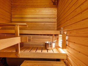 A sauna with wooden benches and a metal container, likely for water or steam. - Korpipalo (ent. yllästunnelma 2 b 7) by Interhome (Ylläsjärvi)