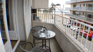 Un balcon avec une table et des chaises, donnant sur un parking et sur un immeuble doté de balcons.