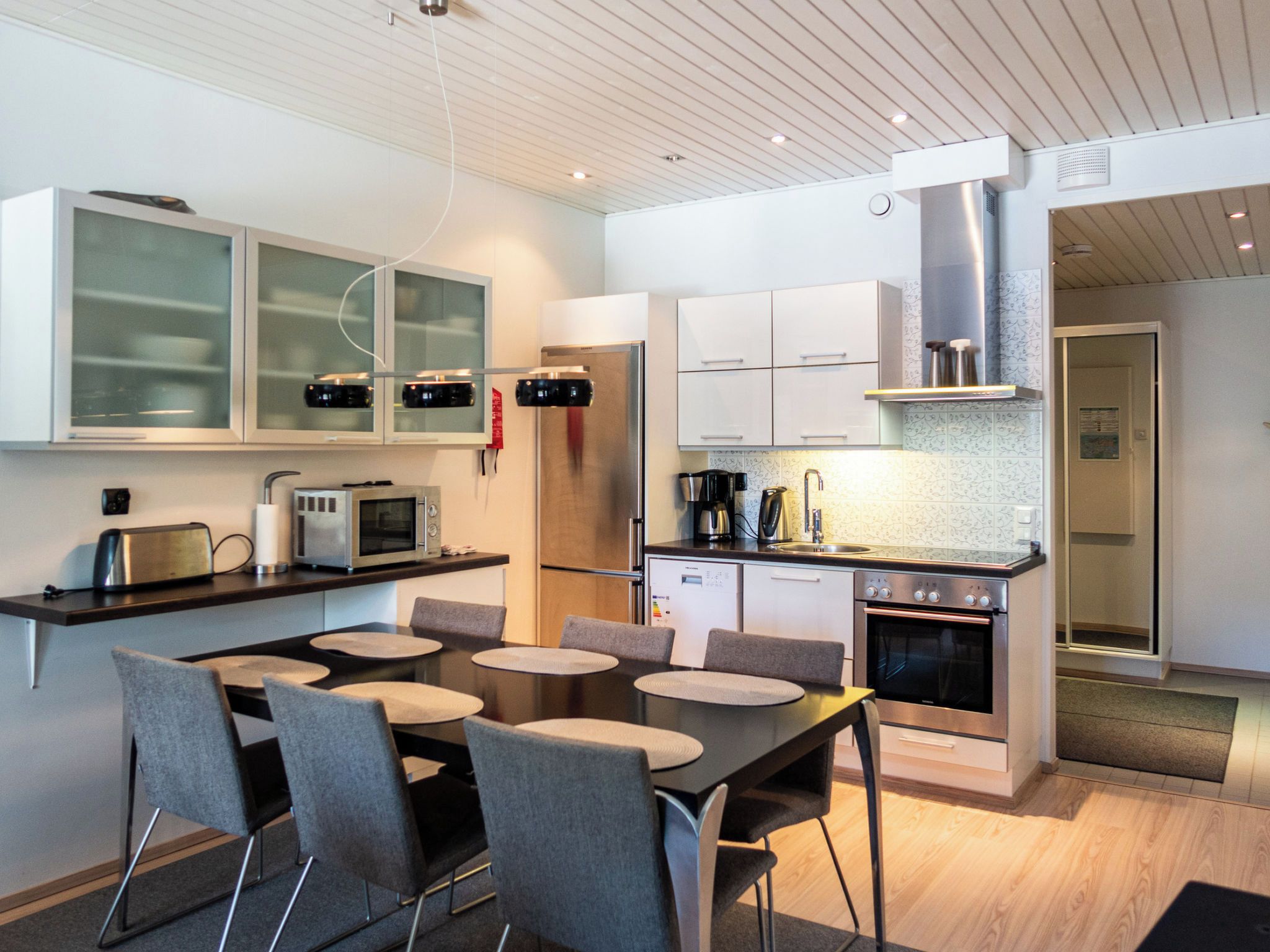 A modern kitchen with a dining area, featuring stainless steel appliances, a built-in oven, and a microwave.