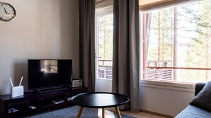 A modern living room with a flat-screen TV, a small table, and a sofa.