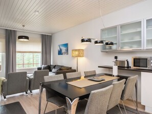 Een moderne keuken met een magnetron, fornuis en een eethoek met stoelen en een tafel.