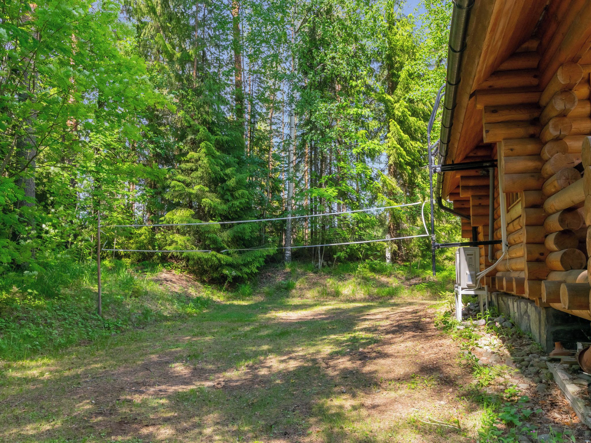A log cabin with a dirt path leading to a wooden fence.