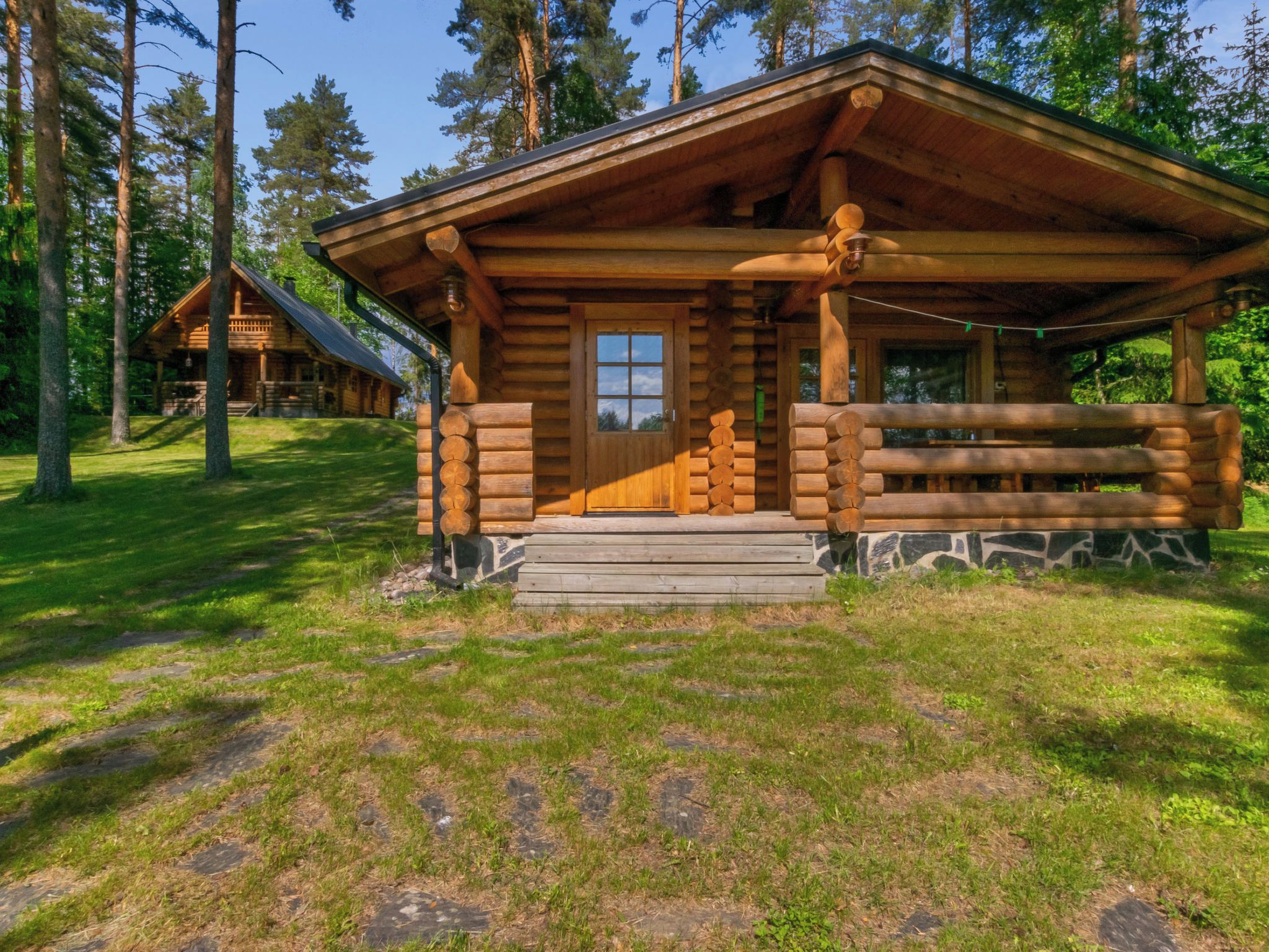 A wooden cabin with a porch, surrounded by trees.