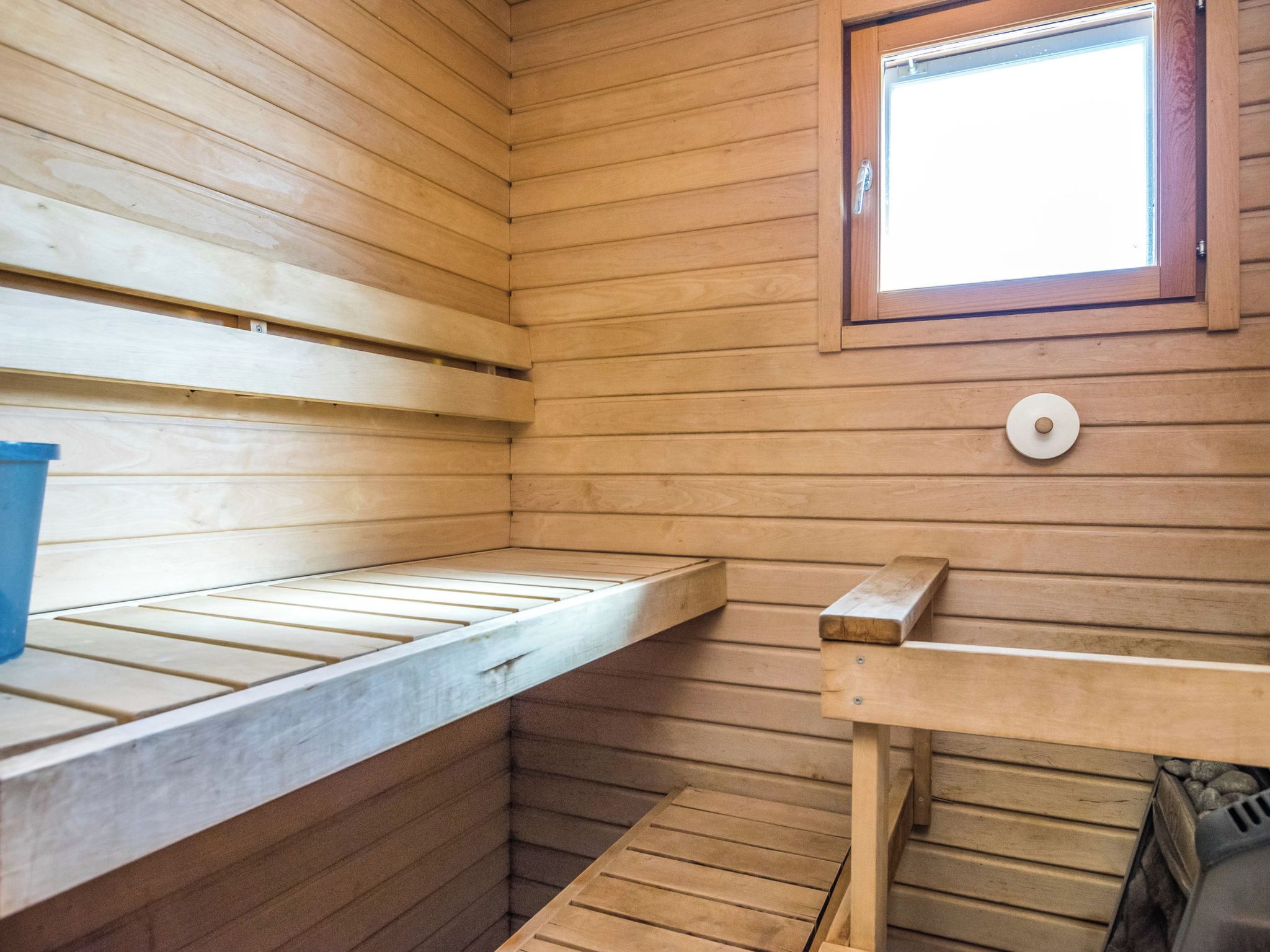 Una sala de sauna con paredes de madera, un banco y una ventana.